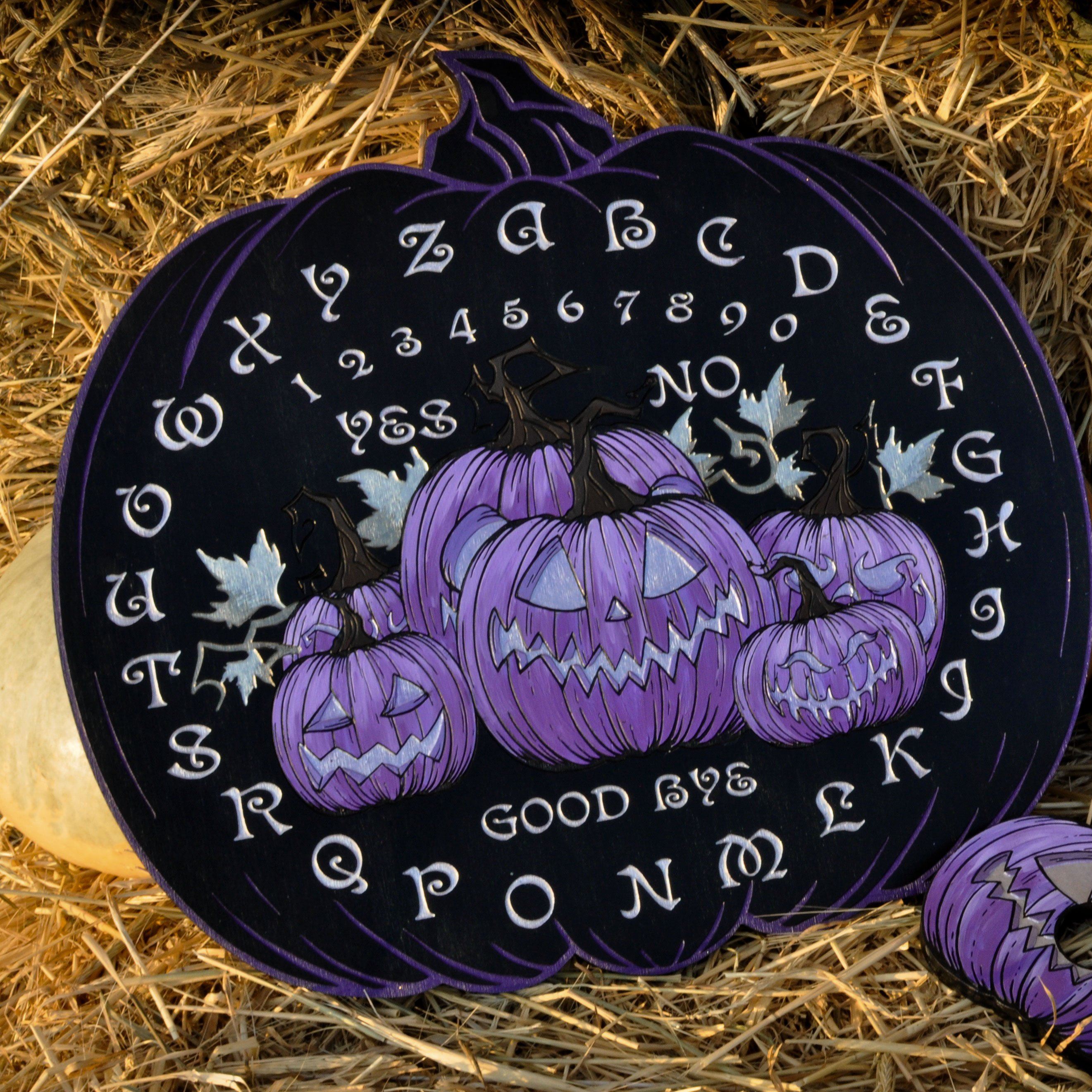 A wooden Ouija board with a Halloween theme, featuring a pumpkin design, engraved letters, and a planchette.