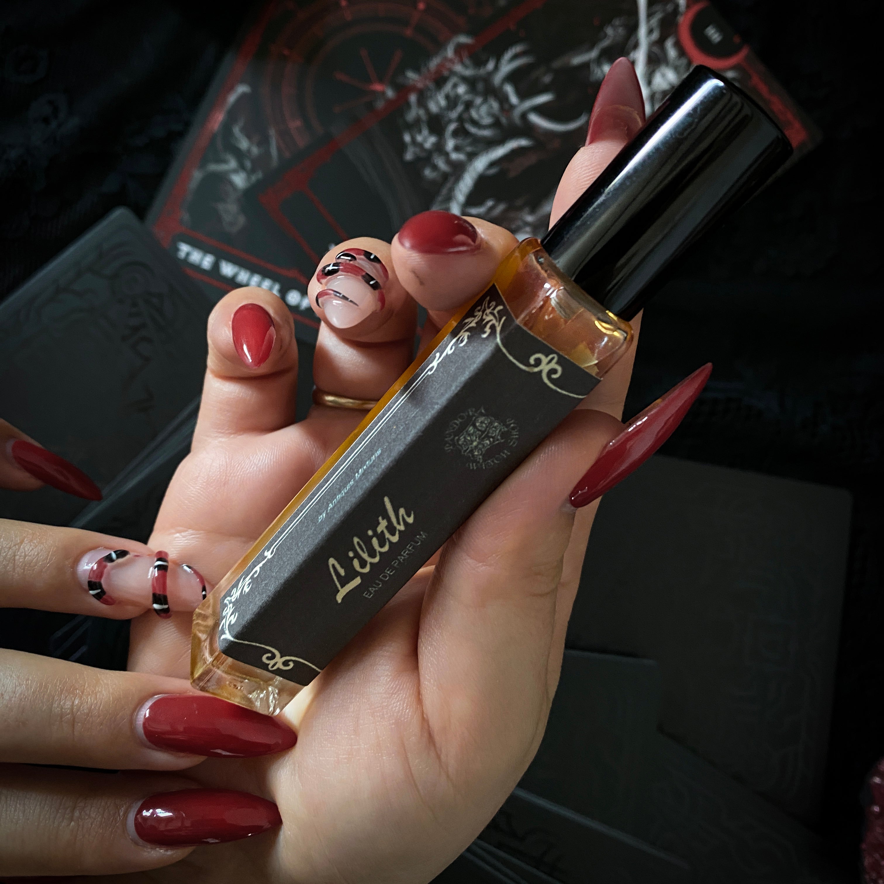 Three black glass bottles of ritual perfumes labeled Lilith, Witching Hour, and Hekate. Styled with dried flowers, candles, and witchcraft accessories on a dark mystical background. Product photo for a witch shop offering international shipping